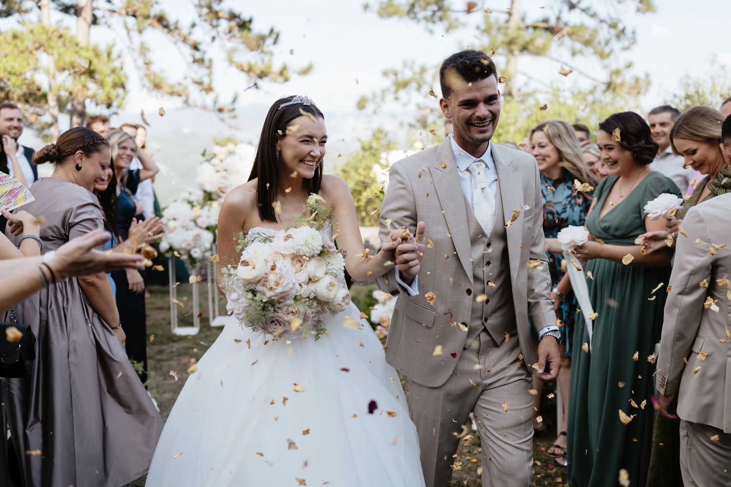 Wedding party celebrates with confetti toss outdoors.