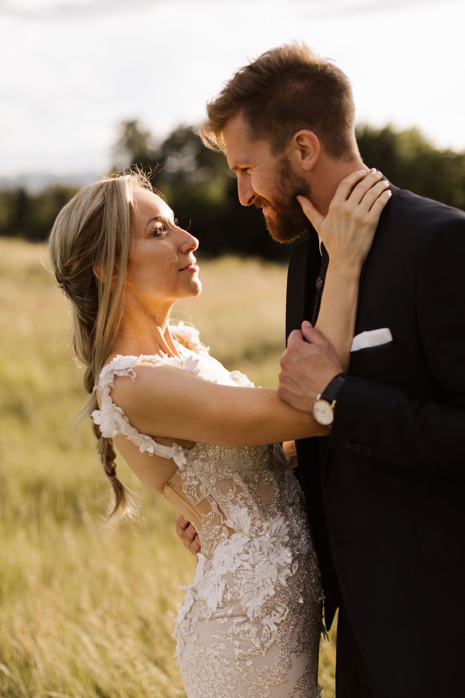 An intimate moment between newlyweds captured in golden sunlight against a natural landscape.