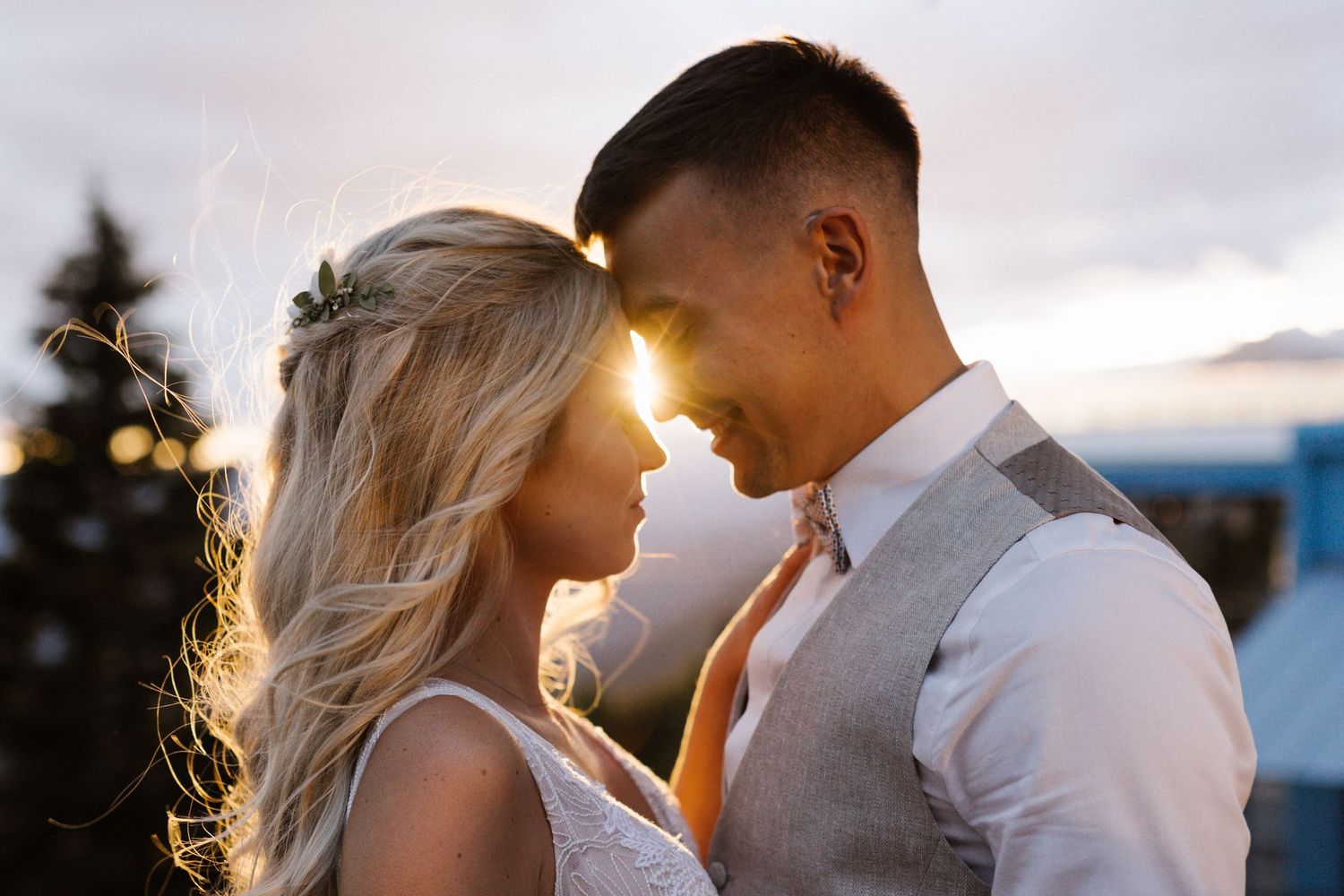 A couple shares an intimate moment at sunset with mountain and lake views in the background.