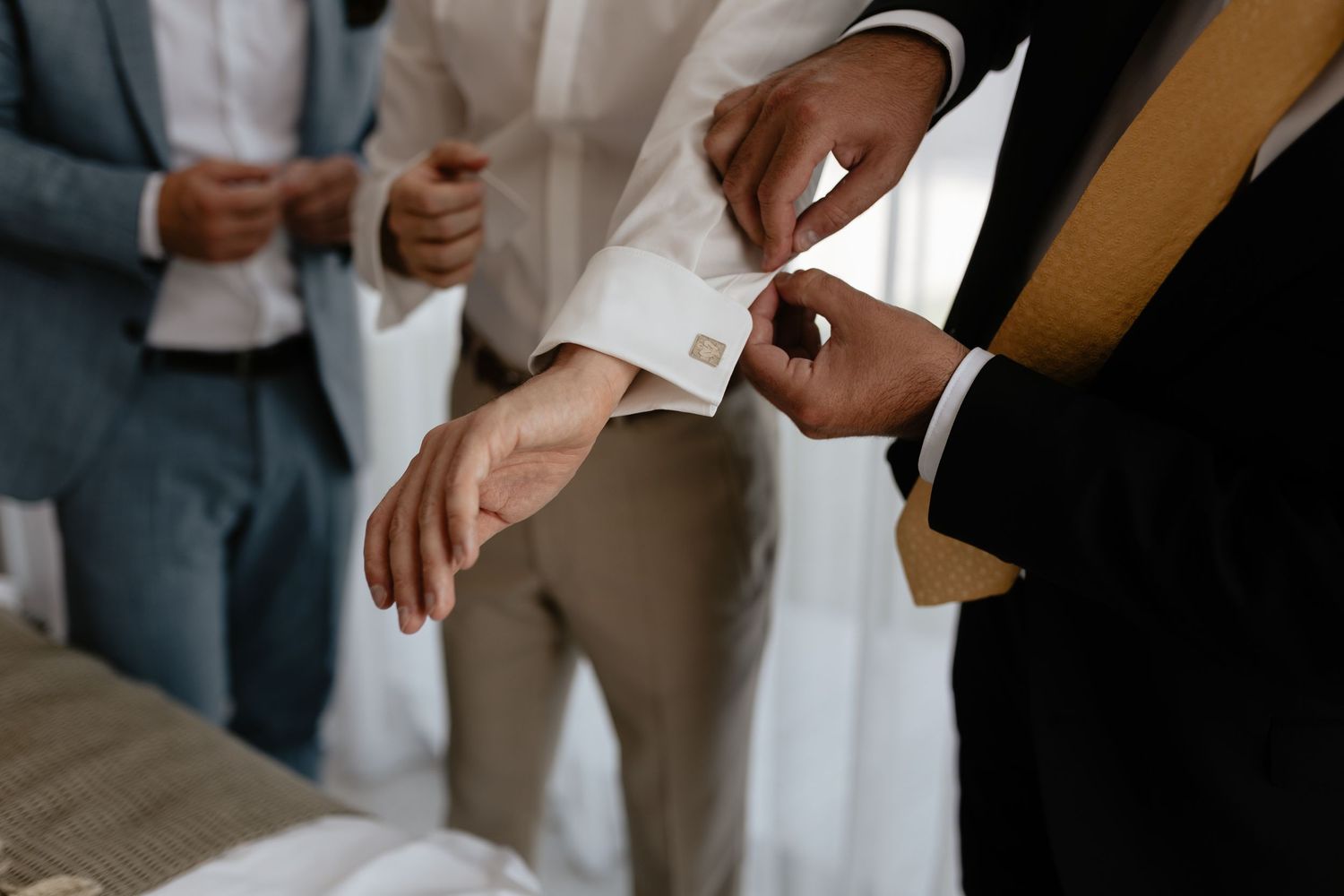 A close-up shot of hands adjusting white dress shirt cuffs during formal attire preparation.