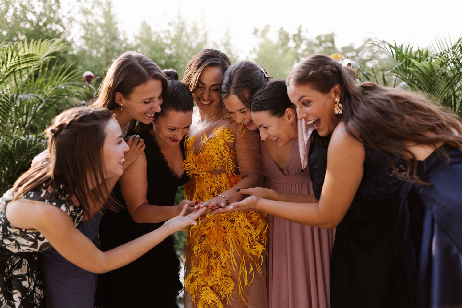A joyful group shares an intimate moment outdoors surrounded by greenery.