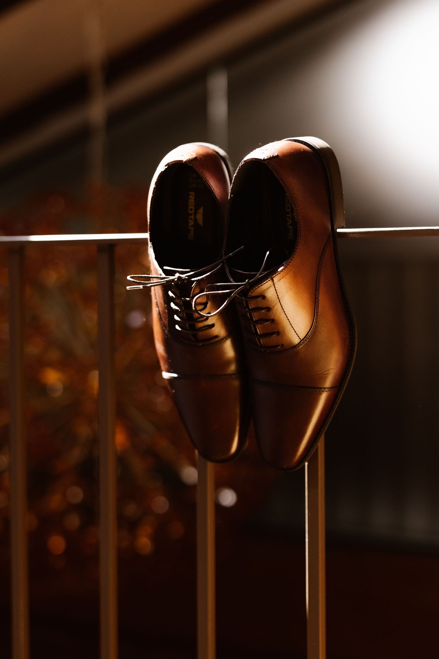 A row of elegant black dress shoes lined up against a dark background with dramatic lighting.