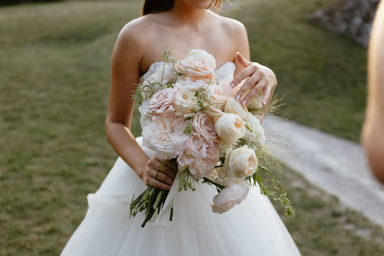 Beautiful white peony and rose wedding bouquet against bridal gown.