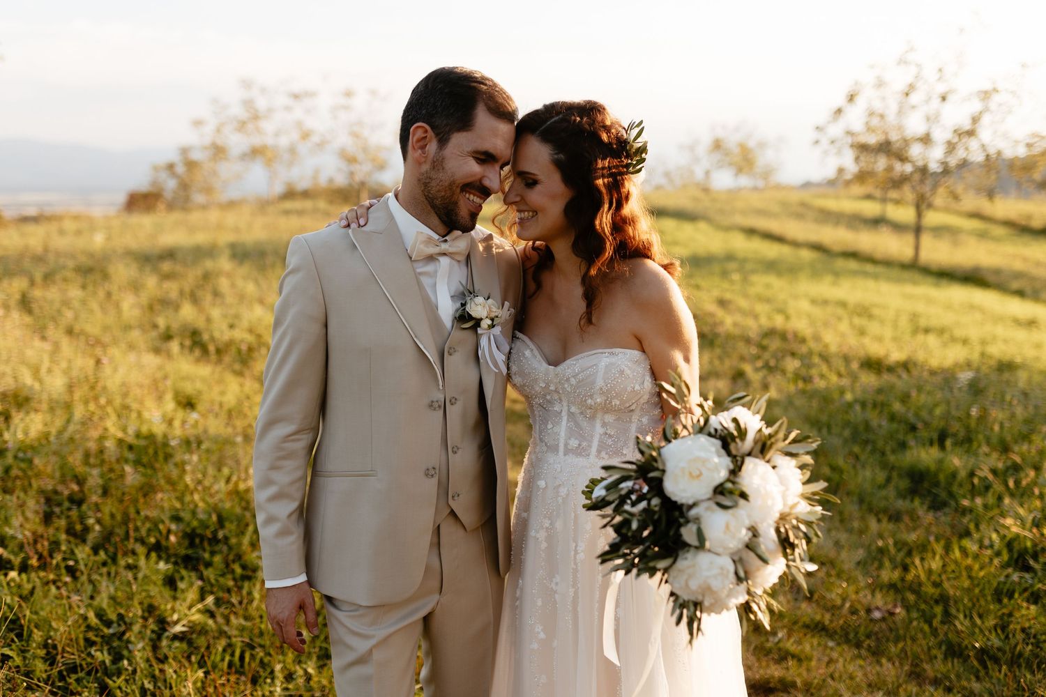 Couple shares an intimate moment during golden hour in a scenic mountain meadow setting.