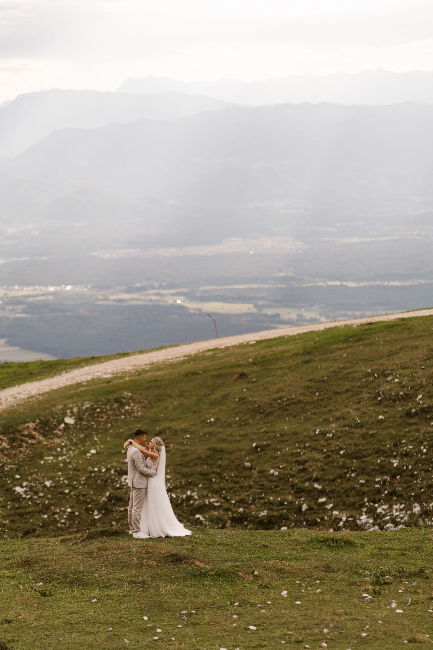 A scenic mountain landscape with rolling hills and distant peaks under cloudy skies.