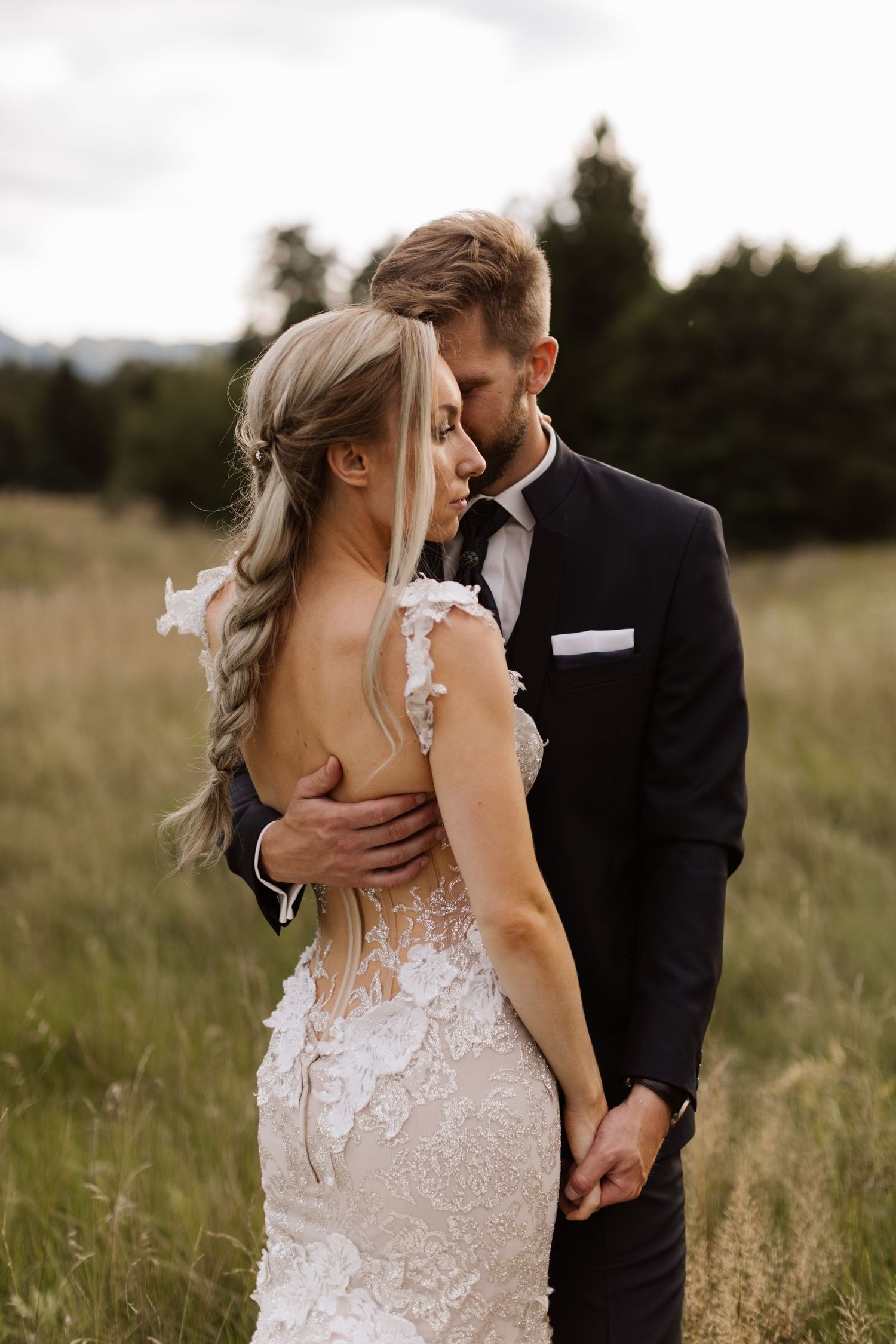 A romantic wedding portrait of a couple embracing in a golden field at sunset.