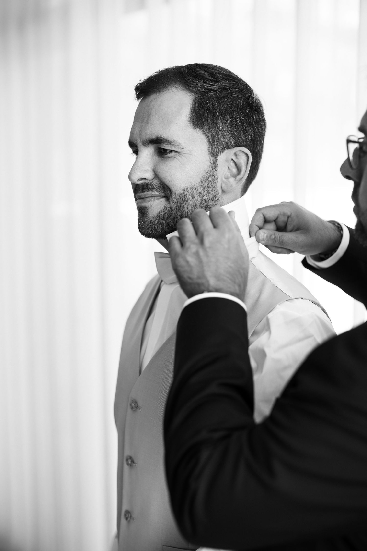 Black and white photo sequence showing a groom getting ready and adjusting his tie before the wedding ceremony.