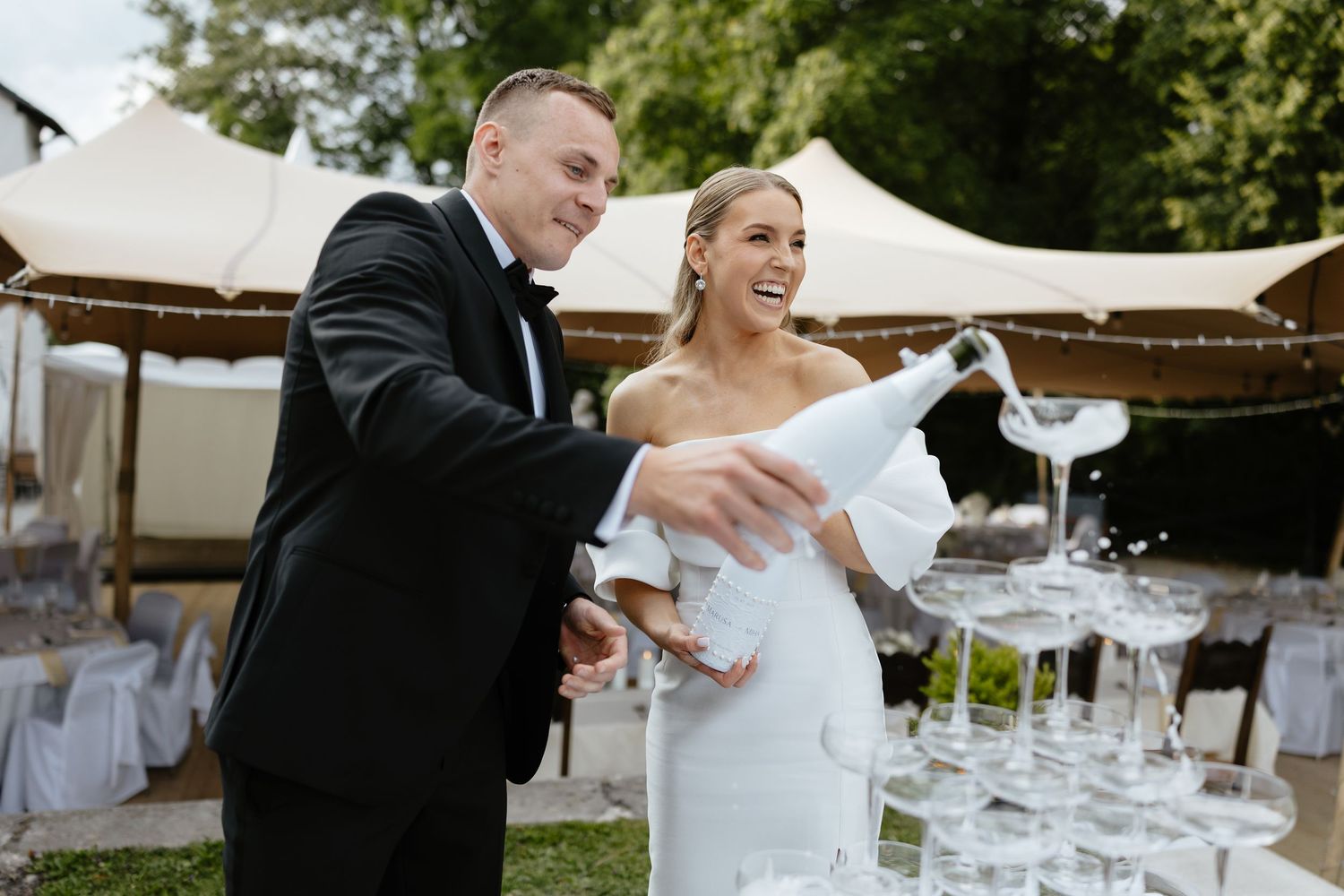 Champagne being poured into glasses at an outdoor wedding reception.