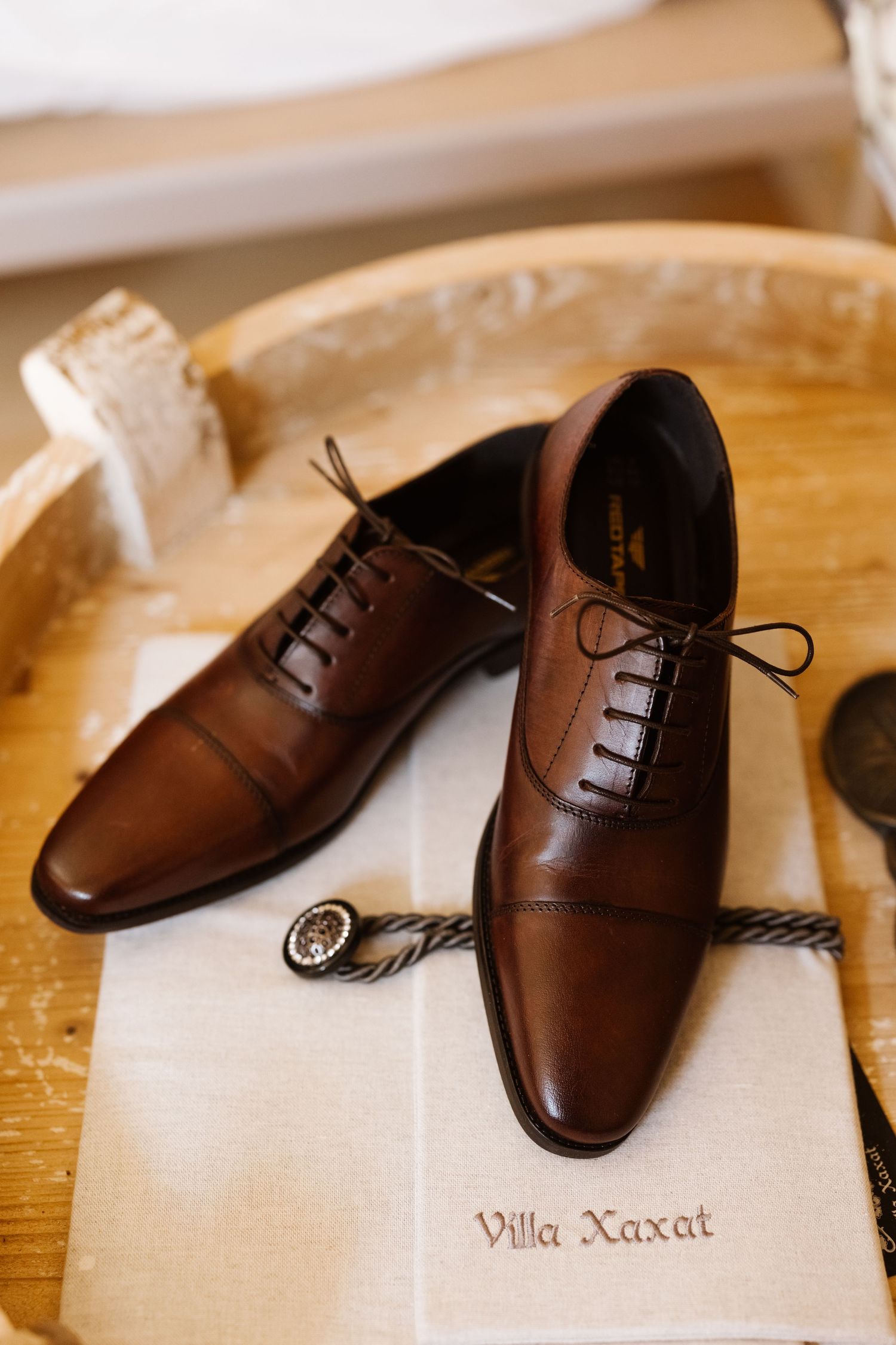 Elegant brown leather dress shoes arranged in a row on a wooden surface with Villa Xaxat text visible.
