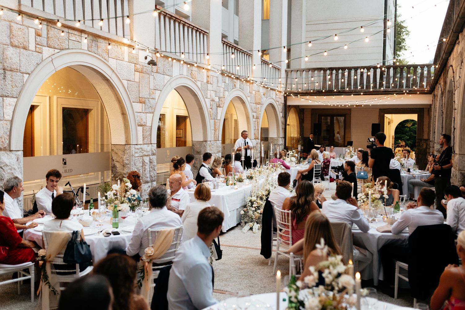 Wedding reception venue with stone archways and elegant table settings under warm lighting.