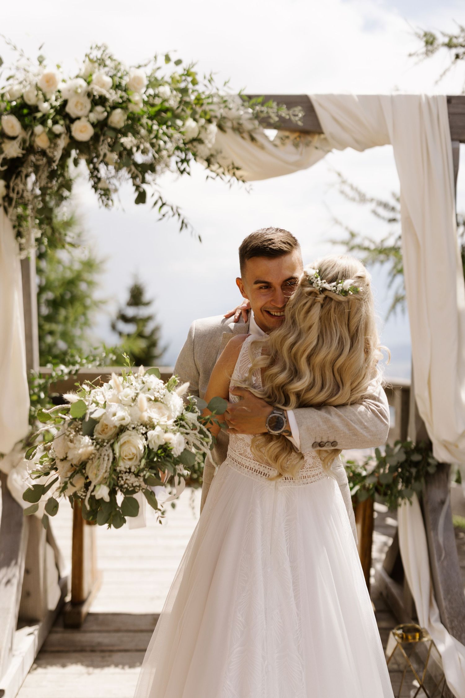 A romantic wedding moment captured in a series of photos showing a couple embracing under white floral decorations.