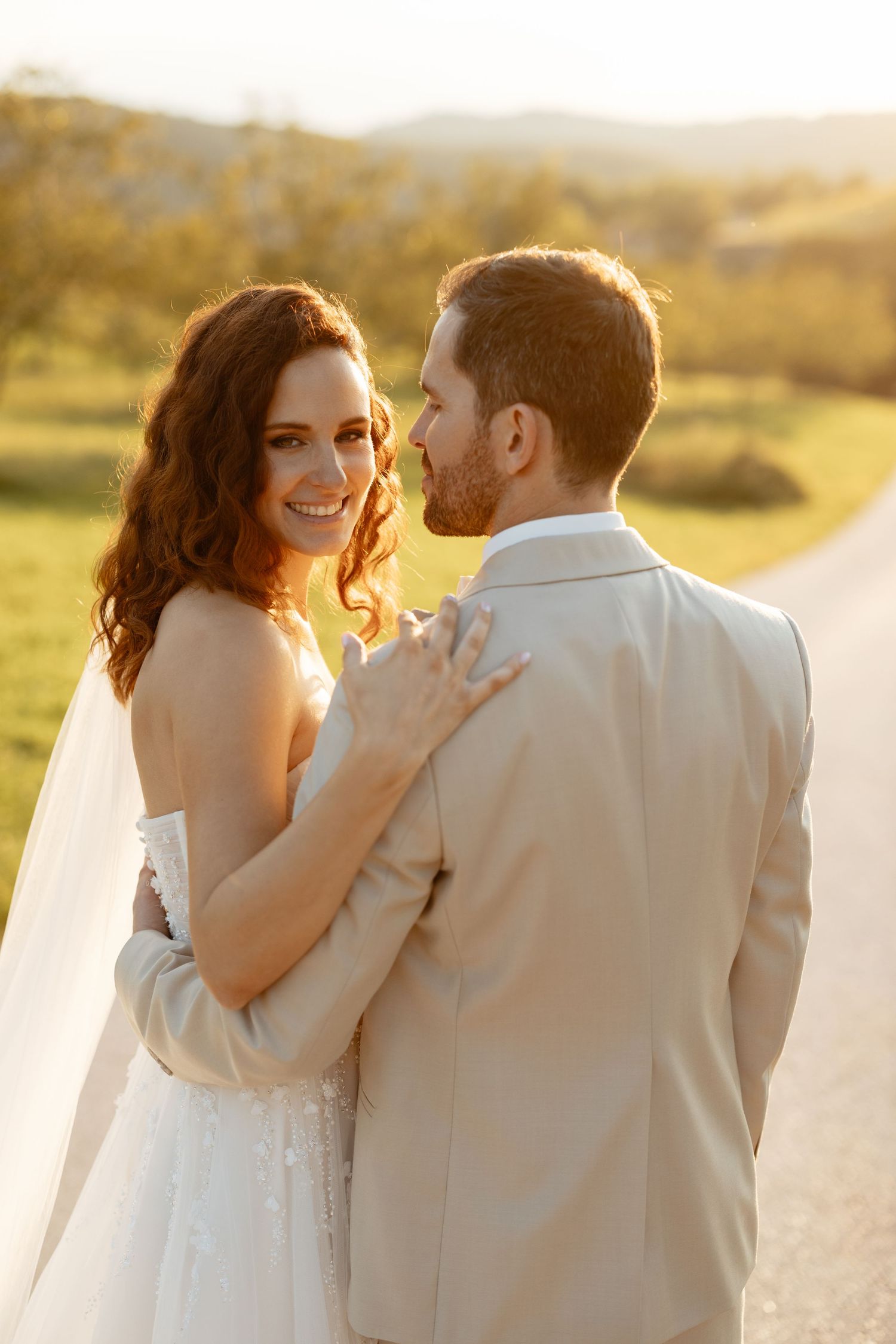 Romantic sunset wedding photos capture tender moments between newlyweds on a golden-lit path.