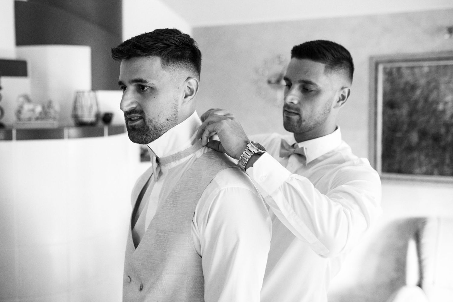 Professional barber wearing white shirt gives a haircut to client in classic barbershop setting.