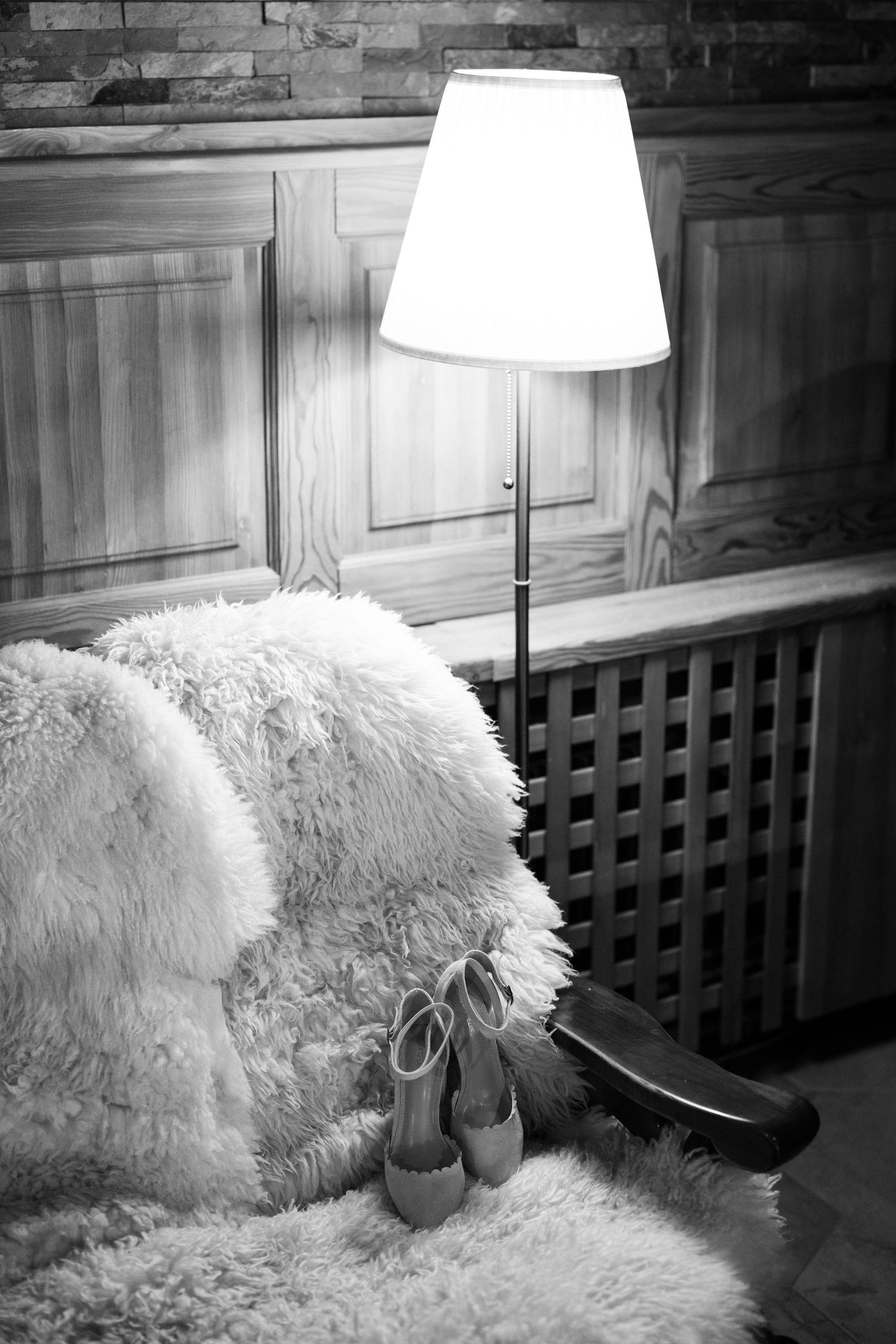 A cozy interior scene with white fluffy pillows and a table lamp against a rustic wooden wall.