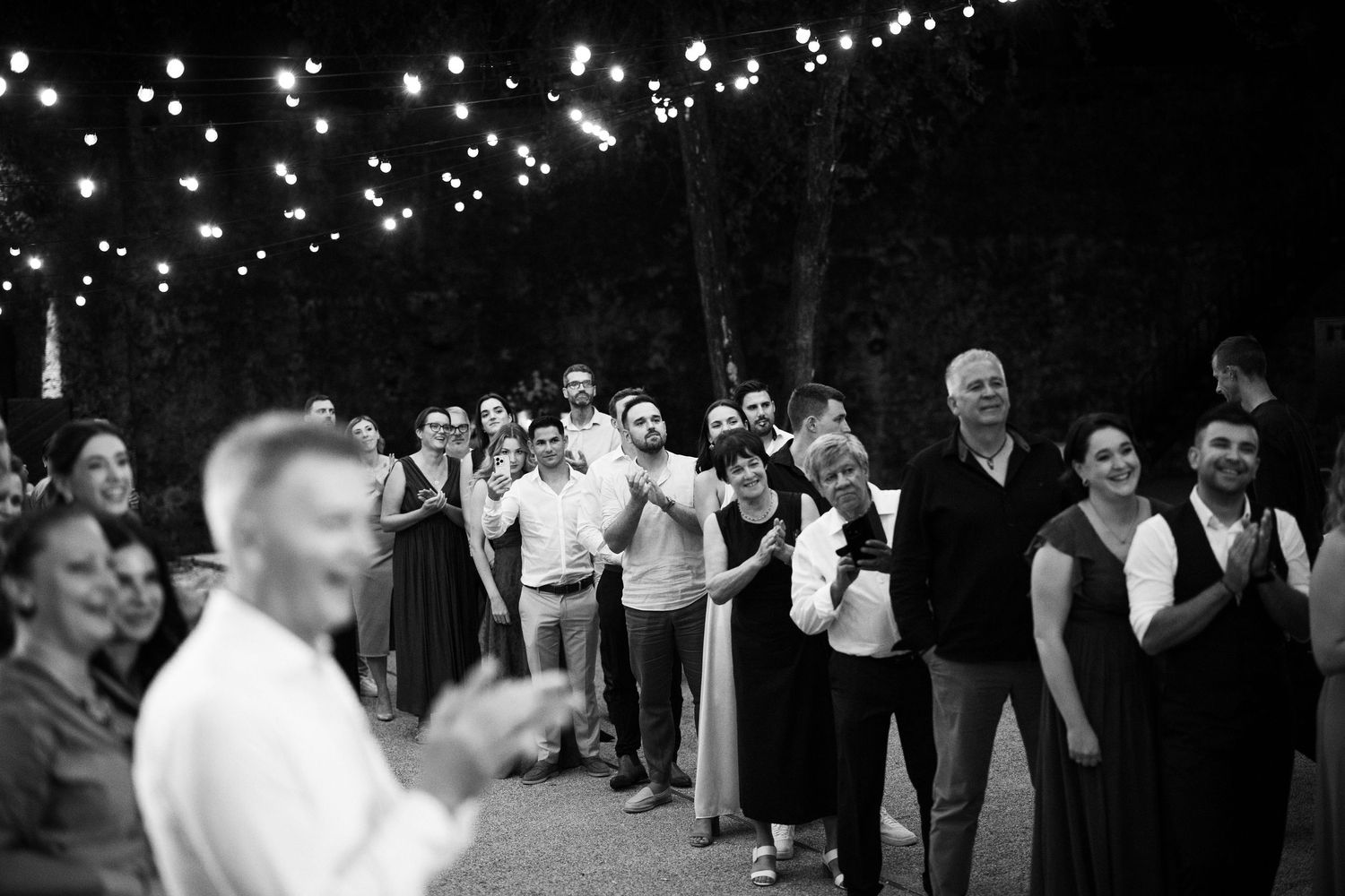 Wedding celebration at night with string lights illuminating dancing guests.