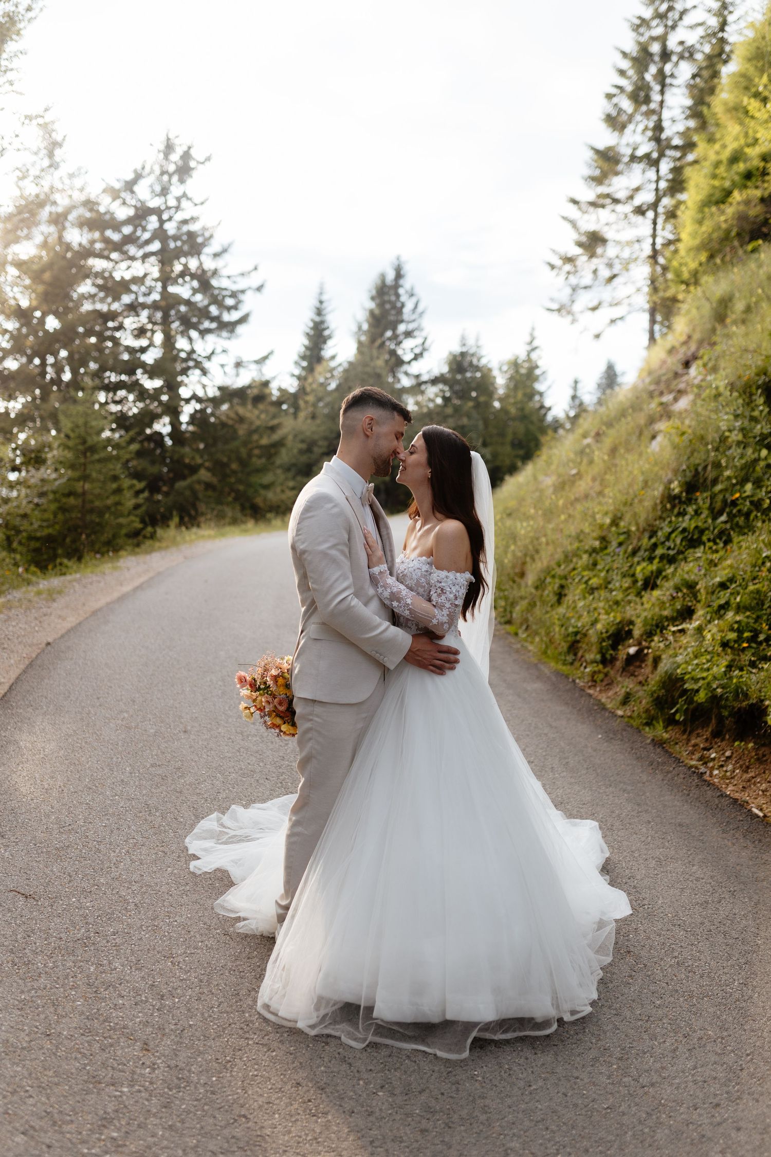 Romantic wedding couple embracing on a tree-lined path during golden hour.