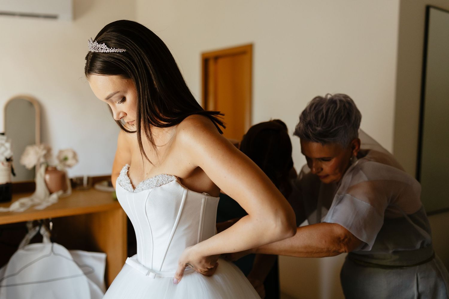 Wedding preparation scene with white dress being adjusted.