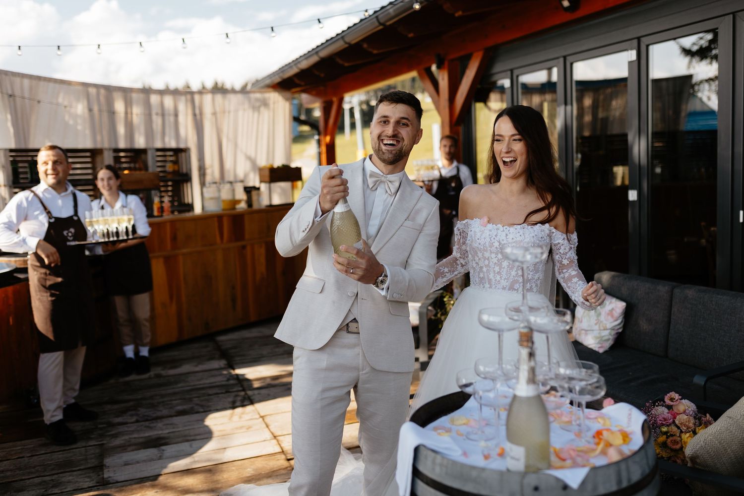 A celebratory moment at a rustic outdoor reception venue with string lights and wooden decor.