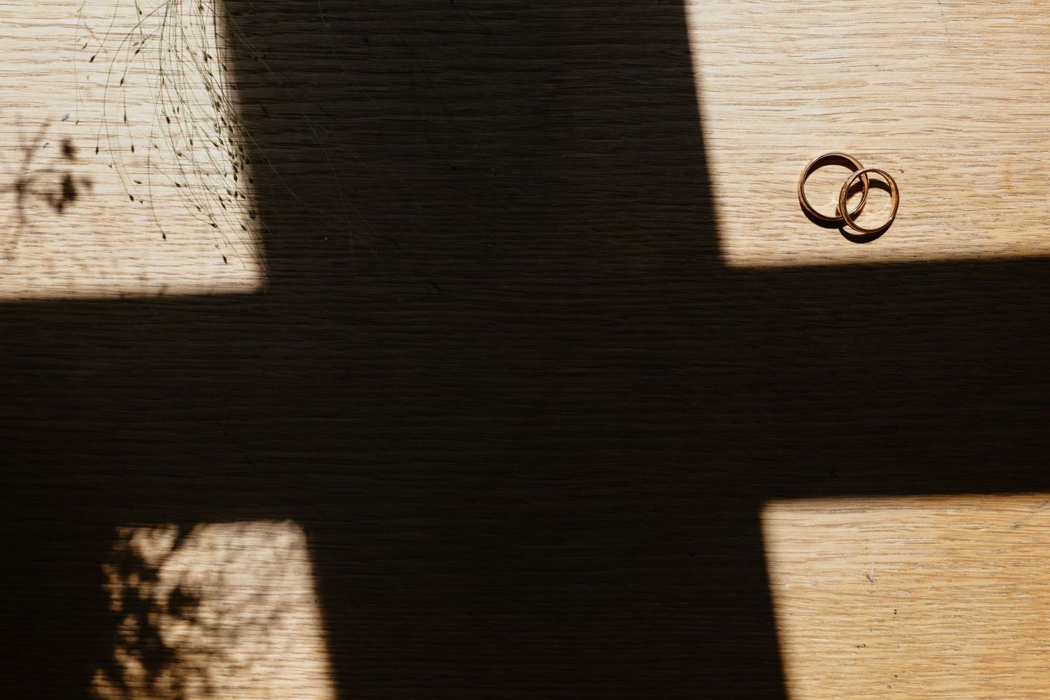 A perfume bottle and brown suede moccasins arranged on a dark surface with soft lighting.