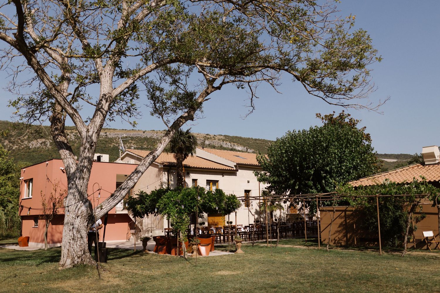 Panoramic view of a rustic villa property with terracotta buildings and trees in the countryside.