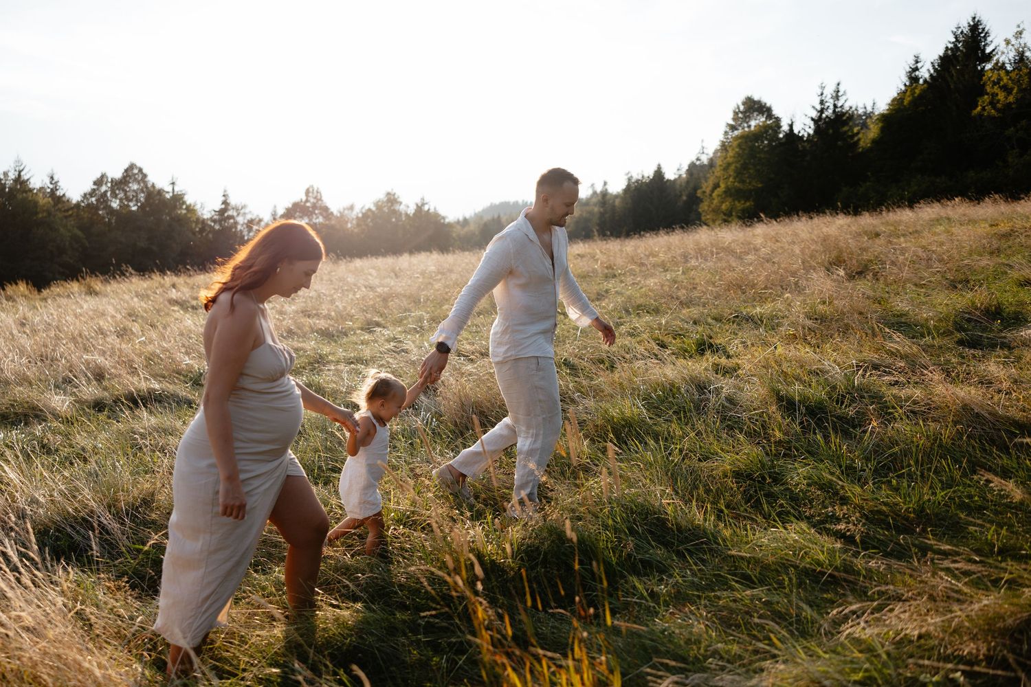 Family walking through tall grass during golden hour photography session.