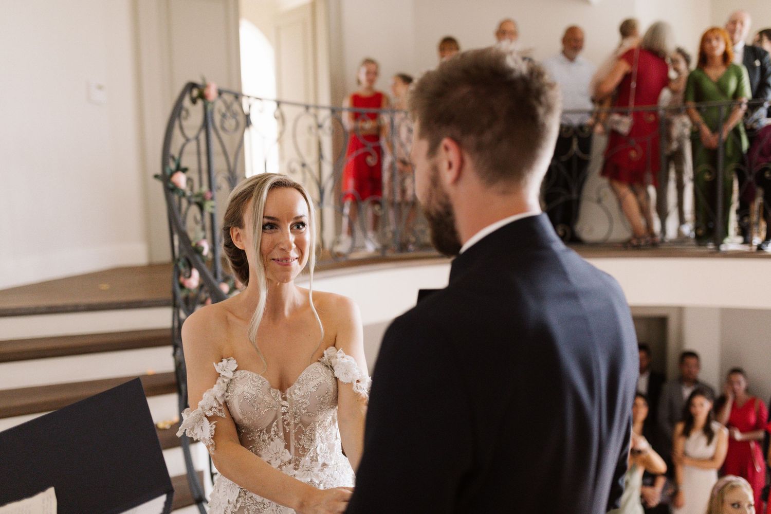 Wedding ceremony taking place in an elegant indoor venue with guests watching the celebration.