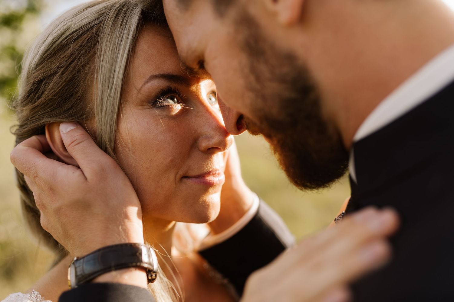 Intimate close-up shot of newlyweds sharing a tender moment outdoors.