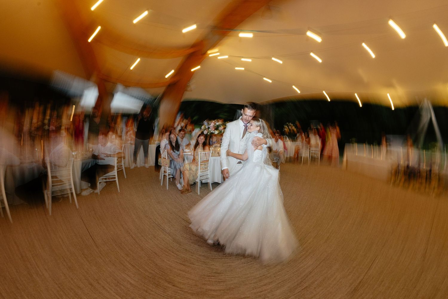 Motion-blurred photo of a first dance at a wedding reception with light streaks.