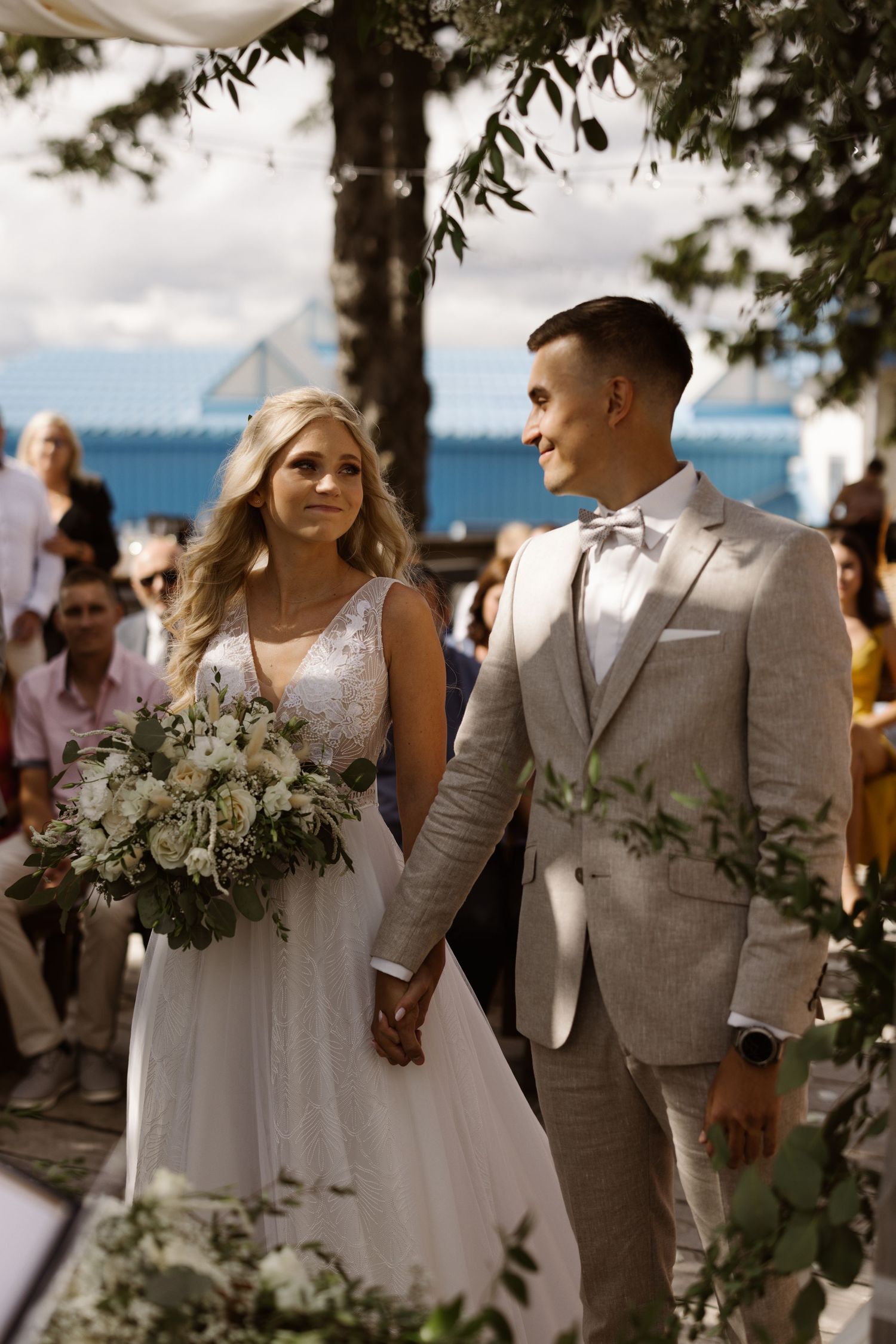 Outdoor wedding ceremony with white floral arrangements and natural decor against a waterfront backdrop.