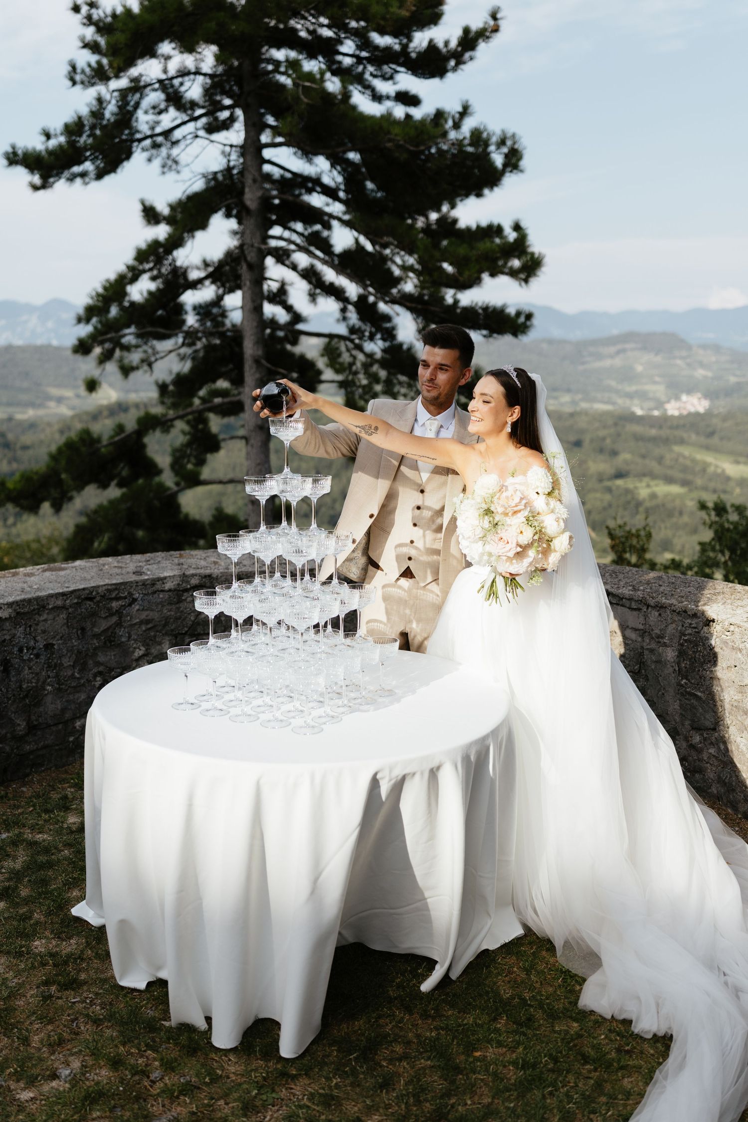 White-clothed tables with champagne glasses set against mountain landscape backdrop.