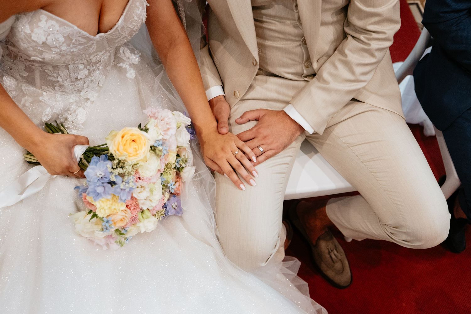 Close-up of newlyweds sitting together with a pastel floral bouquet.