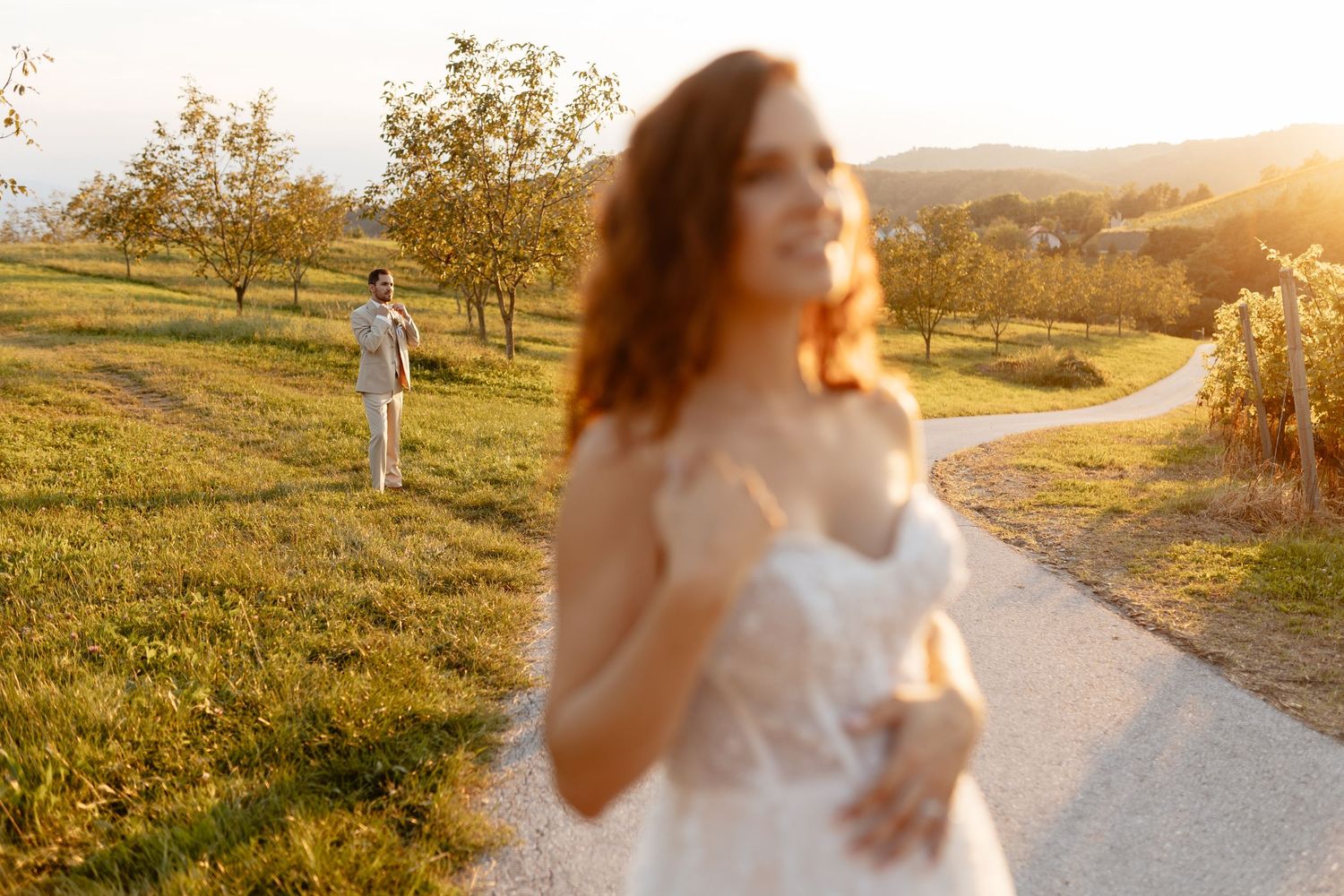 Ethereal bridal portraits captured in dreamy sunlit field with flowing white gown and natural landscape.