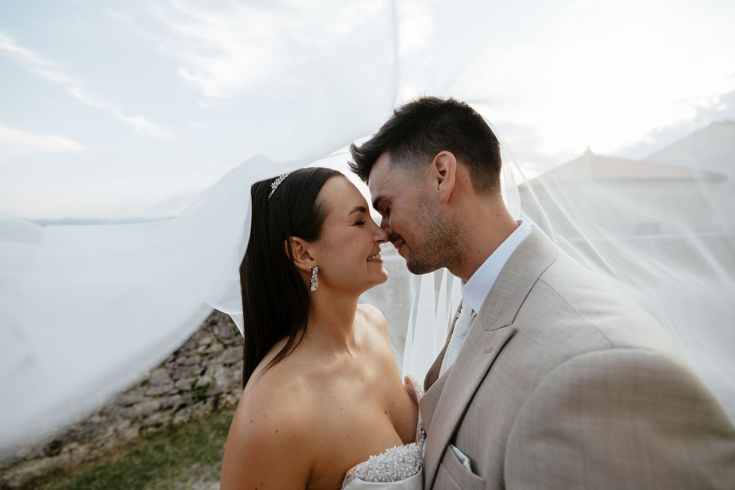 Intimate wedding portraits captured against bright sky with soft natural lighting.
