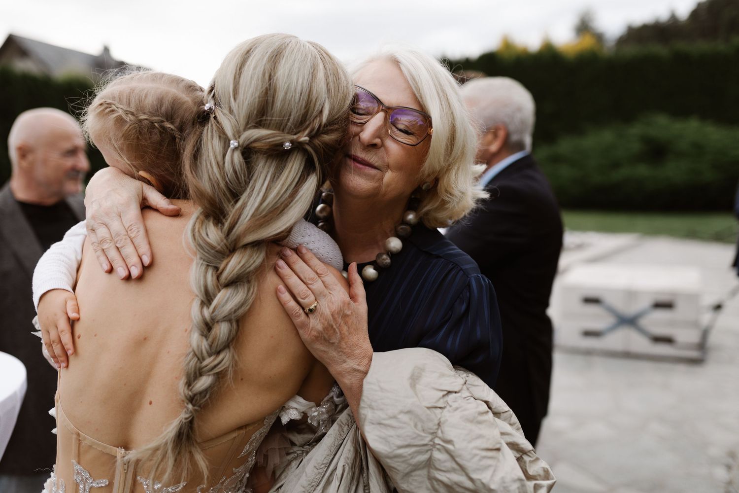 Wedding guests embrace and celebrate during an emotional outdoor reception moment.