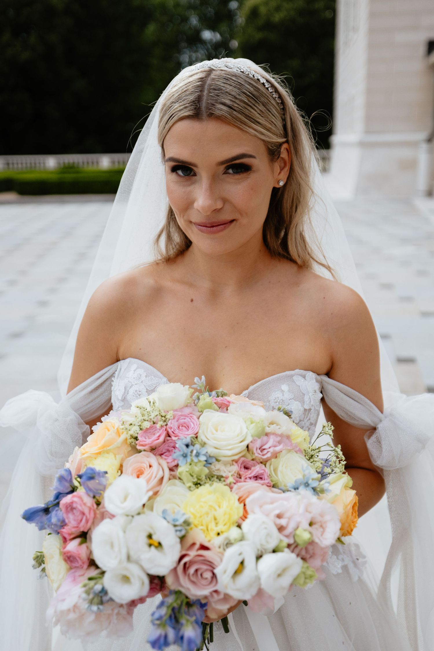 Elegant bridal portrait featuring soft pastel bouquet with roses and delicate spring flowers.