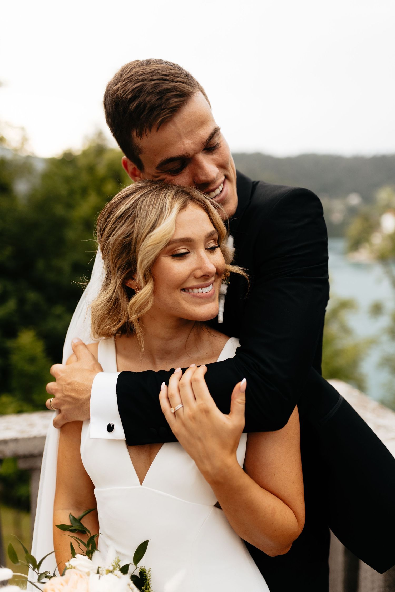 Joyful wedding couple sharing a candid moment on a scenic overlook.