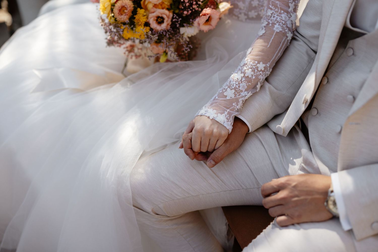 Close-up details of white wedding attire with sunflower decorations and delicate lace elements.