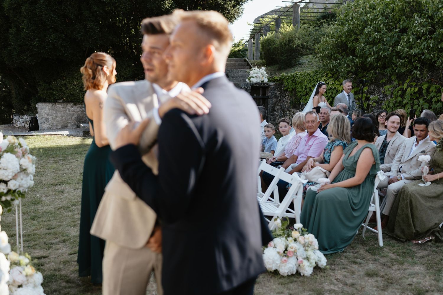 Wedding guests seated outdoors during a garden ceremony.