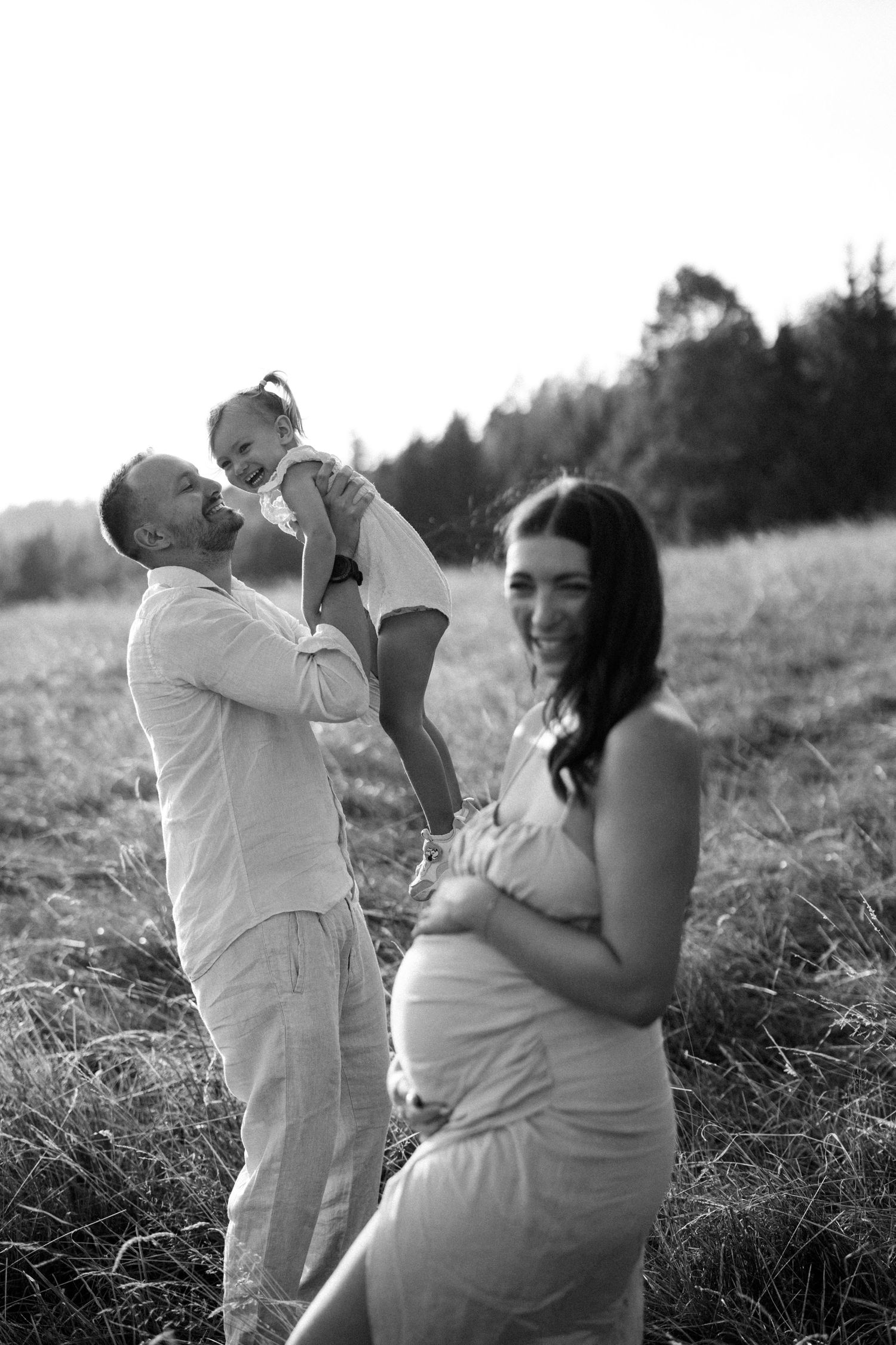 Black and white series of a family embracing in a grassy meadow at sunset.