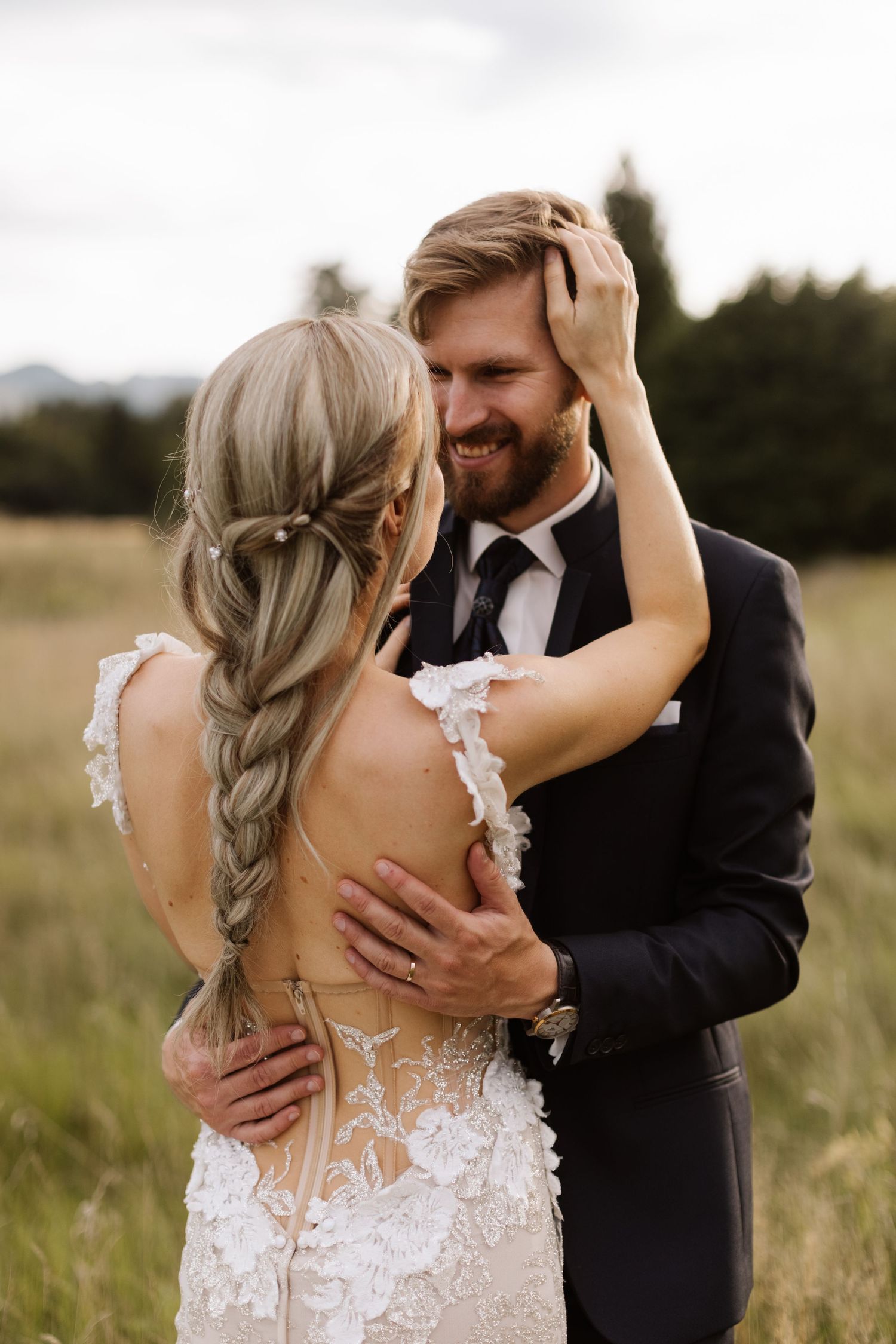 Romantic wedding couple embracing in a sunlit meadow with tall grass.