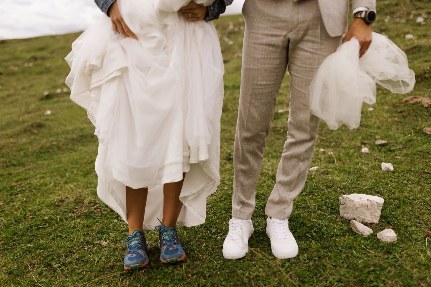 Wedding guests' feet shown in formal shoes and white attire standing on grass at an outdoor celebration.
