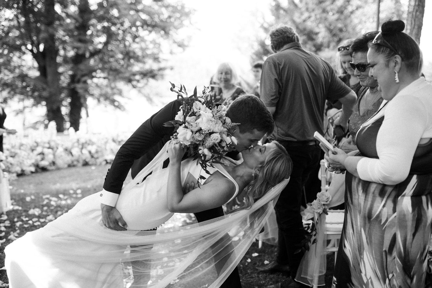 A joyful moment captured during an outdoor wedding celebration with guests gathered around.