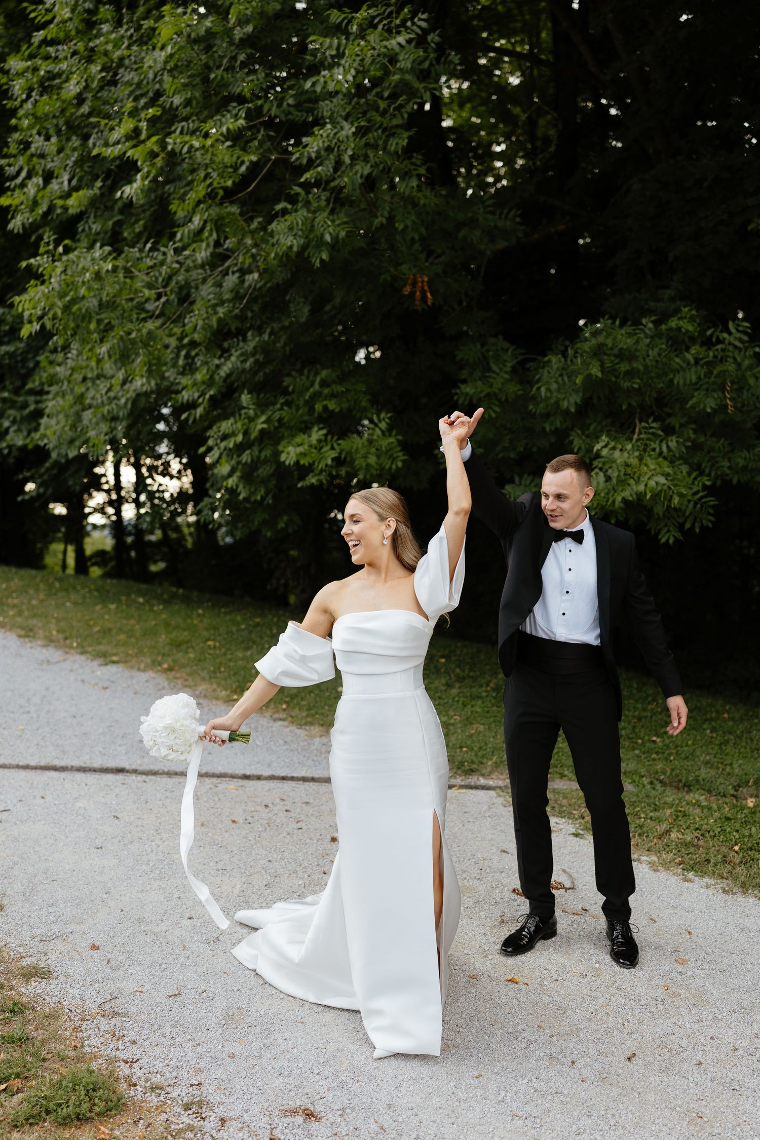 Candid wedding photos on a gravel path showing joyful dancing movements.