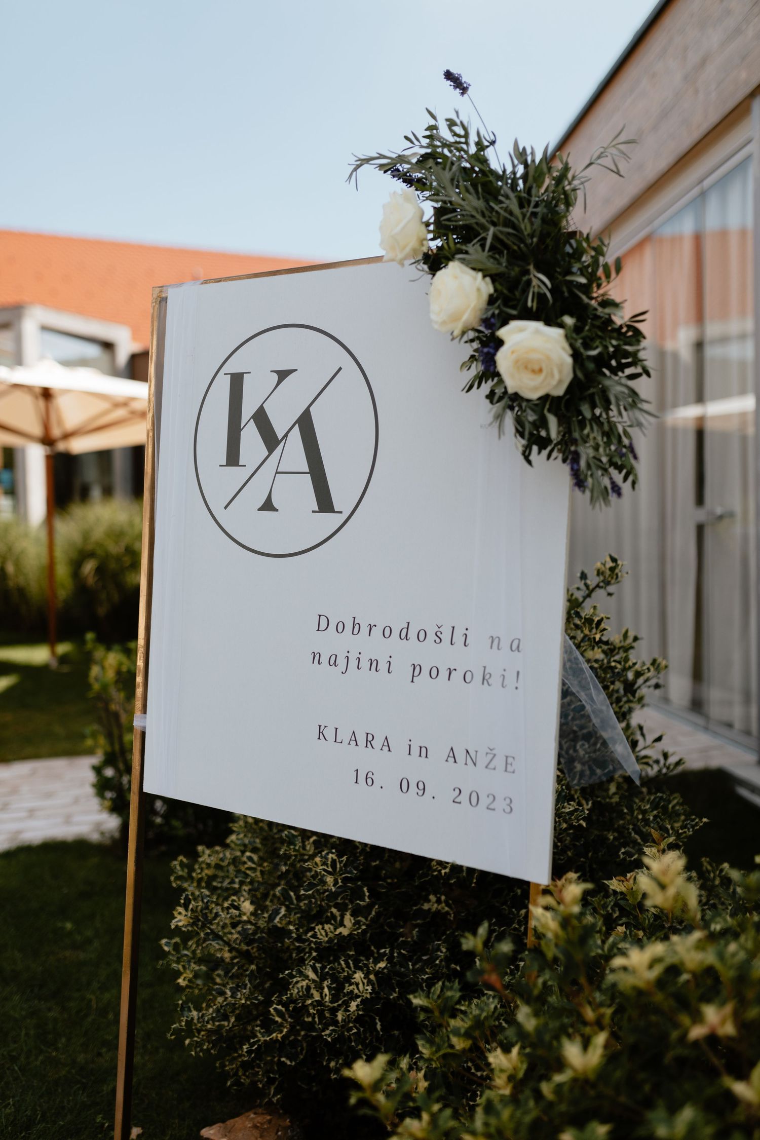 Elegant wedding signage with monogram logo and date displayed on white signs with greenery and floral decorations.