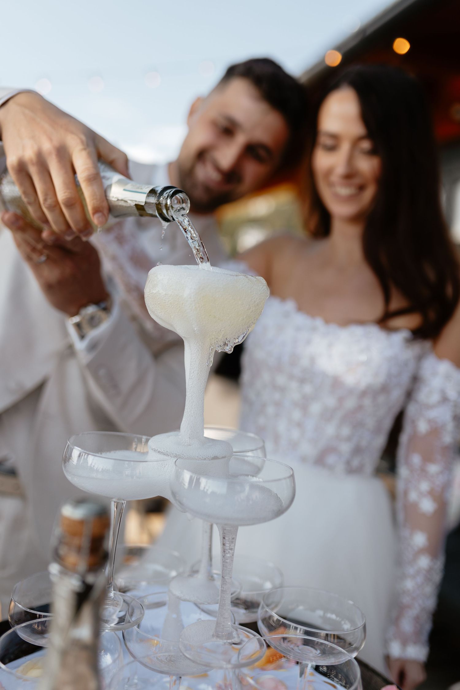 Champagne being poured into a tiered fountain of glasses at an elegant reception.