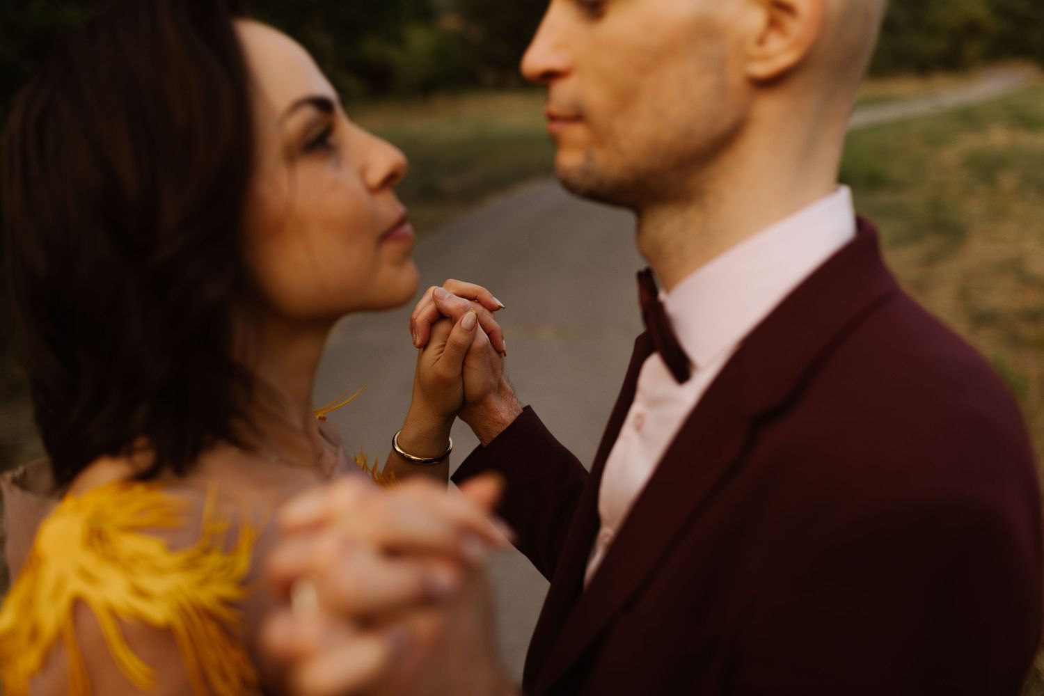 Romantic sunset moment between couple in burgundy and yellow wedding attire.