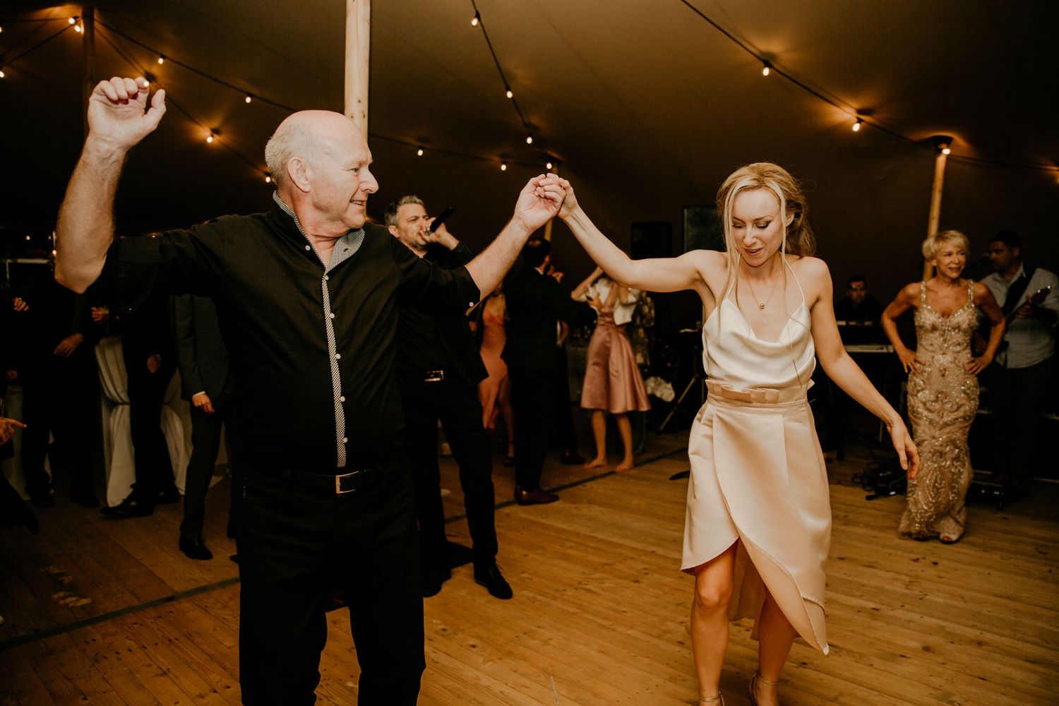 Wedding reception guests dancing and celebrating on a dimly lit dance floor.