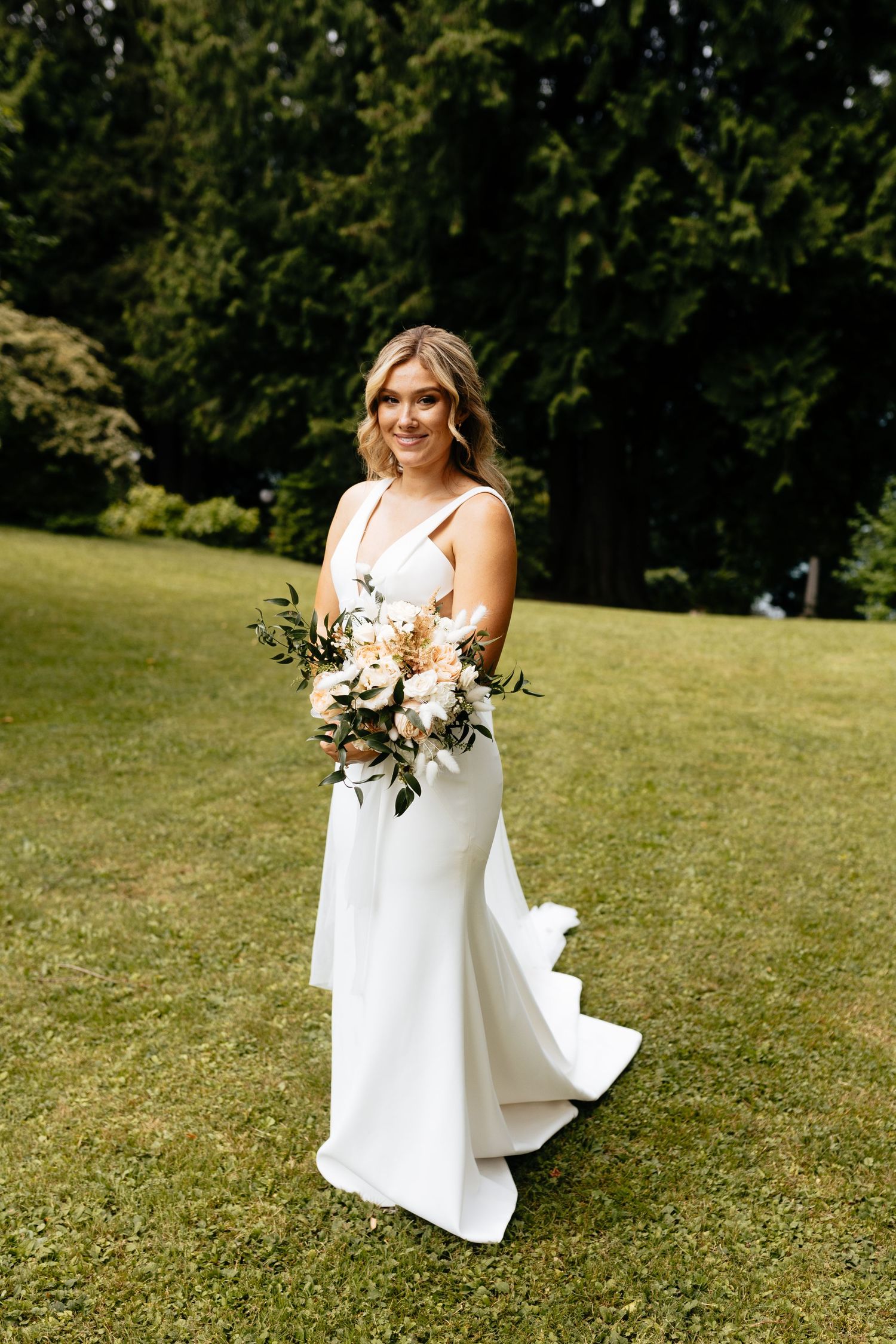 A white wedding gown and bouquet are displayed against a lush green garden backdrop.