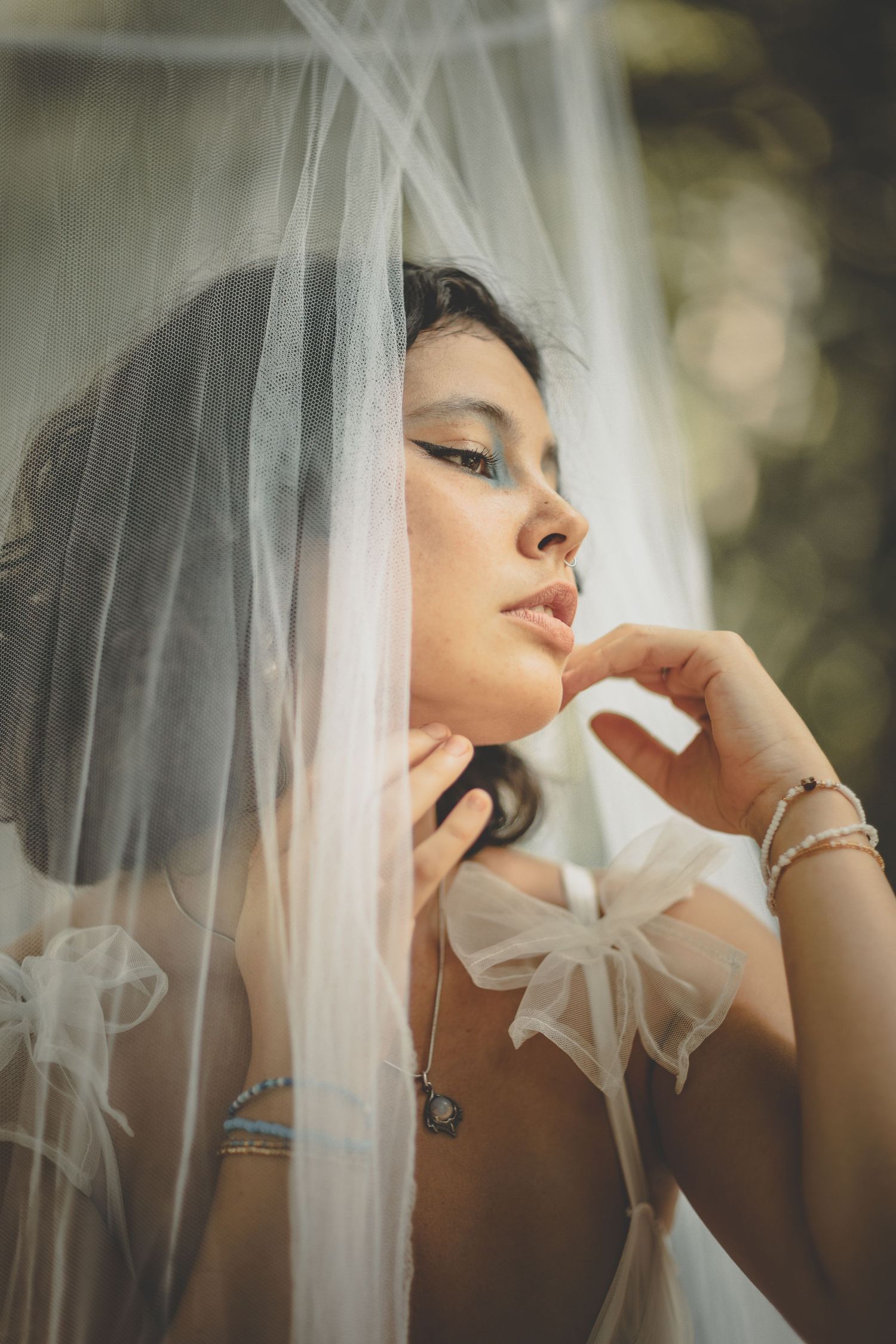 Romantic bridal portraits with soft focus through white tulle veil in natural light.