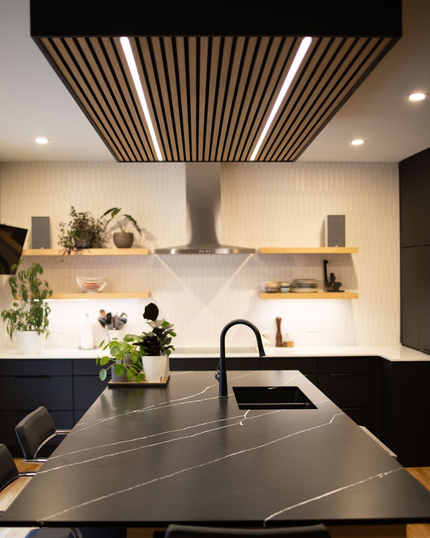 Sleek kitchen interior with black countertops and wooden ceiling details shown in panoramic view.